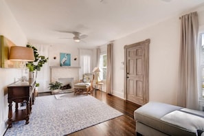 A room with a fireplace, a ceiling fan, and a large wooden door. - The Periwinkle House – Bask Poolside at this Sunlit West Palm Retreat (West Palm Beach)