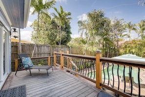 A wooden deck with a chair and a pool in the background. - The Periwinkle House – Bask Poolside at this Sunlit West Palm Retreat (West Palm Beach)