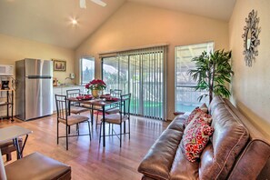 A spacious living area with a dining table, chairs, a sofa, a refrigerator, and a large window with blinds. - Quiet Rental w/ Balcony: 14 Mi to Downtown Houston (Houston)