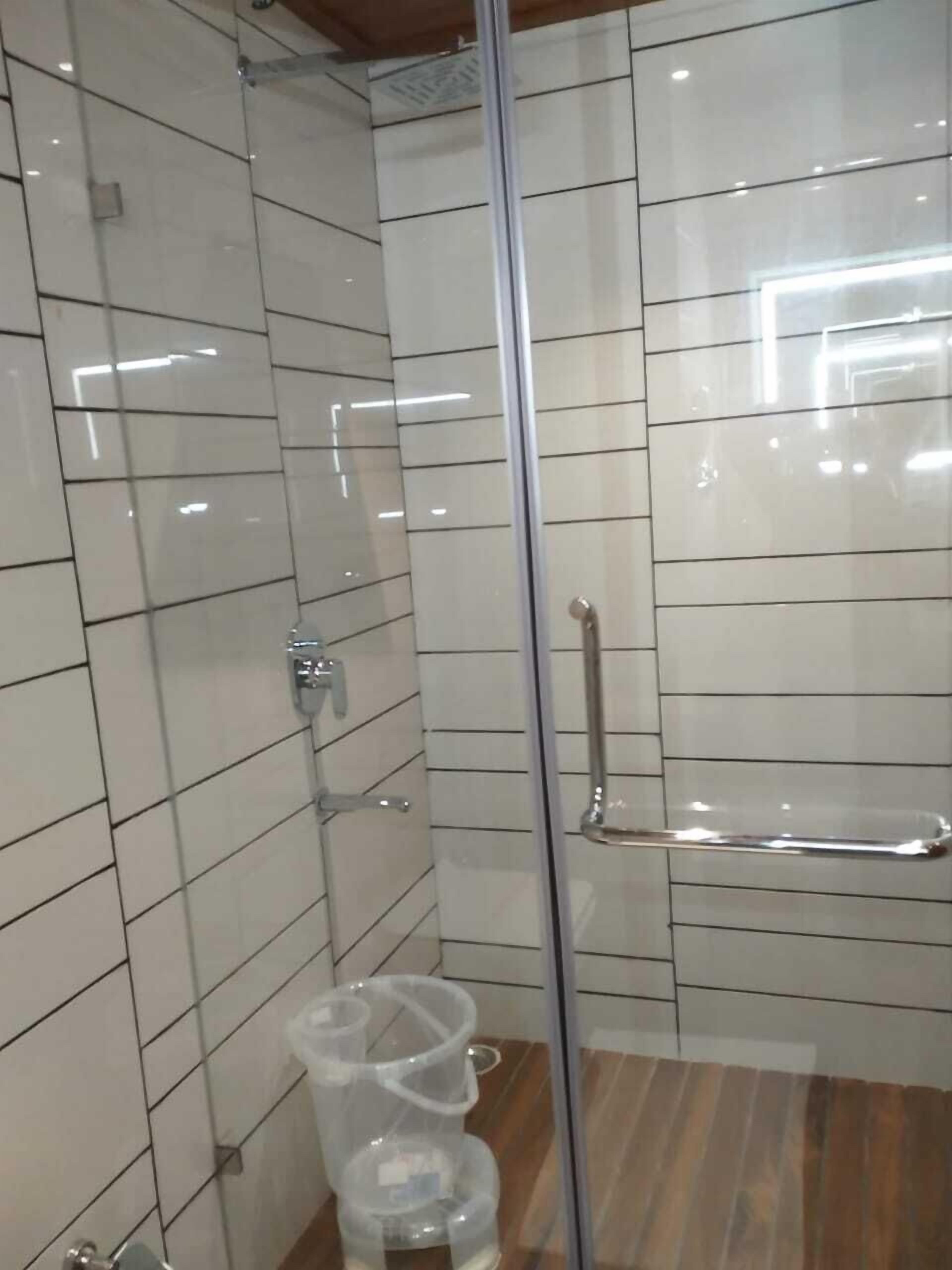 A modern bathroom with a glass shower enclosure, a glass door, and a wooden floor.