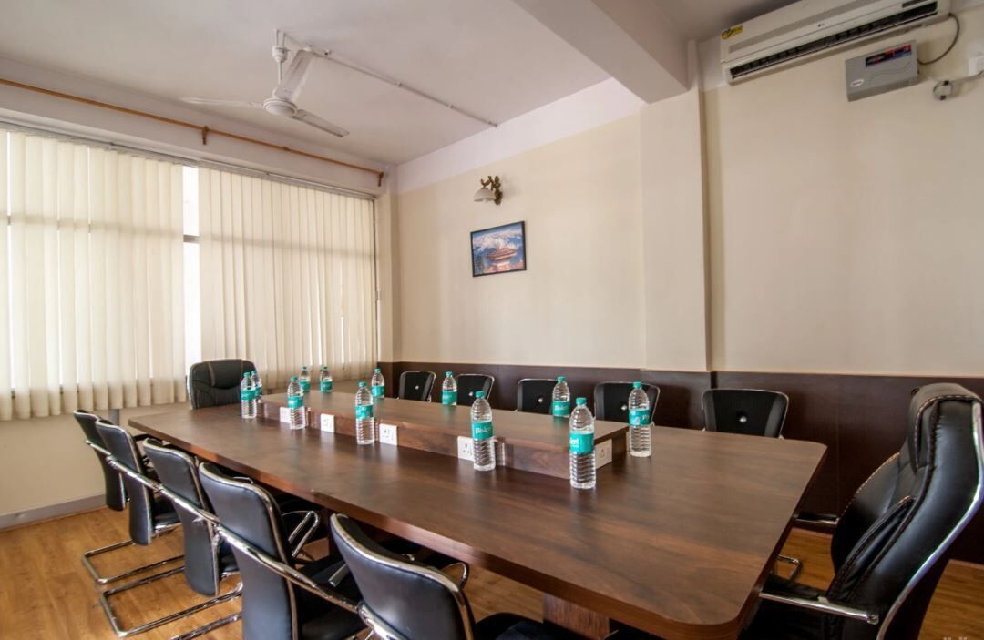 A conference room with a long table, chairs, water bottles, and an air conditioning unit.