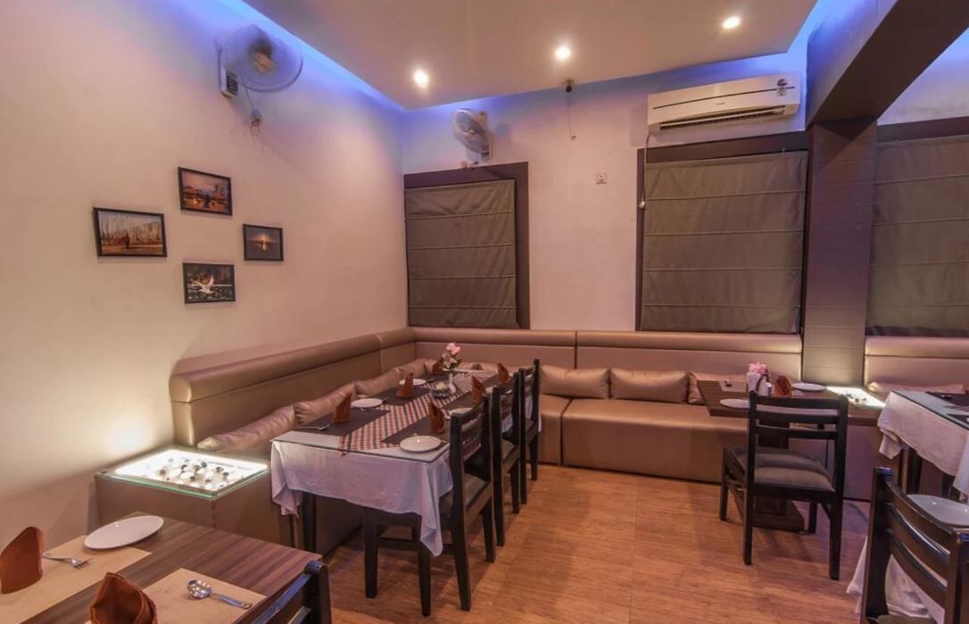 A dining area with a booth seating arrangement, a table set for two, and a sofa.