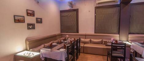 A dining area with a booth seating arrangement, a table set for two, and a sofa.