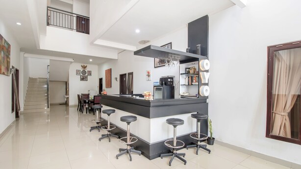 A modern kitchen with a central island, bar stools, and a staircase leading to an upper level.
