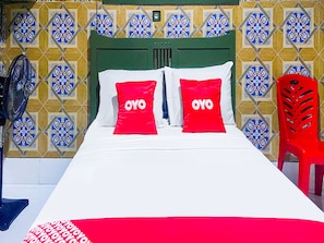 Un lit avec deux oreillers rouges, une tête de lit verte et une chaise rouge.