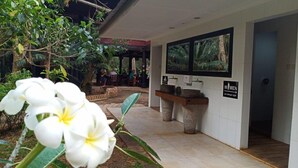 A hotel reception area with a white wall, a reception desk, and a sign indicating women's facilities.