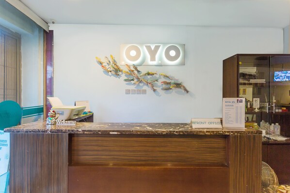 Una mesa de recepción con un cartel de 'Welcome', un cartel de 'ROYAL SPA' y una escultura decorativa de un pez.