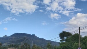A mountain with a flat top, surrounded by greenery and power lines.