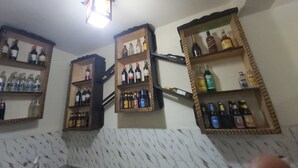 A room with multiple wooden shelves displaying various bottles and glasses, likely for beverages.