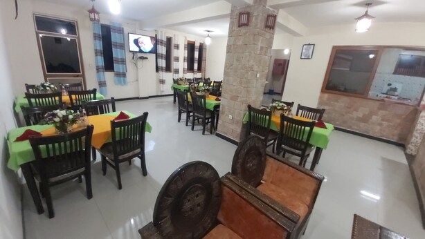 A dining area with multiple tables and chairs, a stone pillar, and a television mounted on the wall.