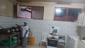A compact kitchen with a stove, refrigerator, and a window overlooking a red-roofed area.