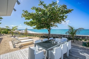 A deck with a table and chairs overlooking a beach.