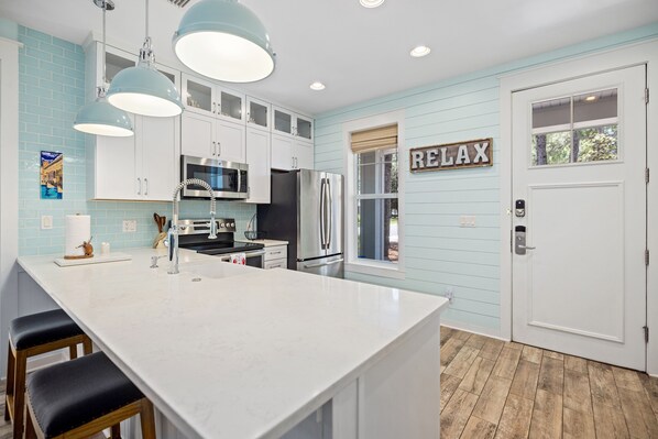 A modern kitchen with white cabinets, stainless steel appliances, and a large island with bar stools.