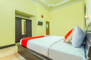 A hotel room with a bed, a television, a door, and a wall clock. - OYO 2848 Senaz Guesthouse (Mataram)