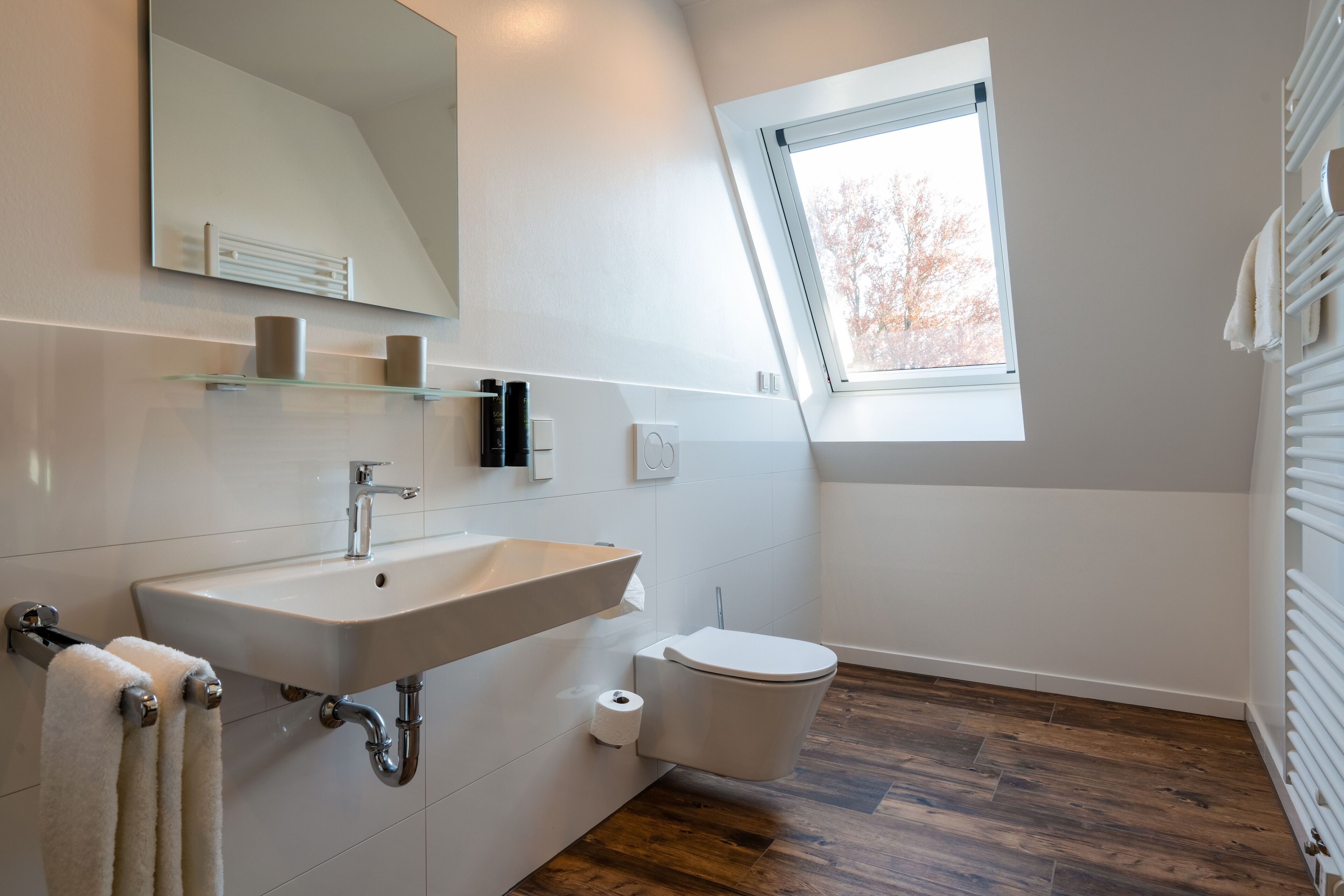 A modern bathroom with a sink, toilet, and a window providing natural light.