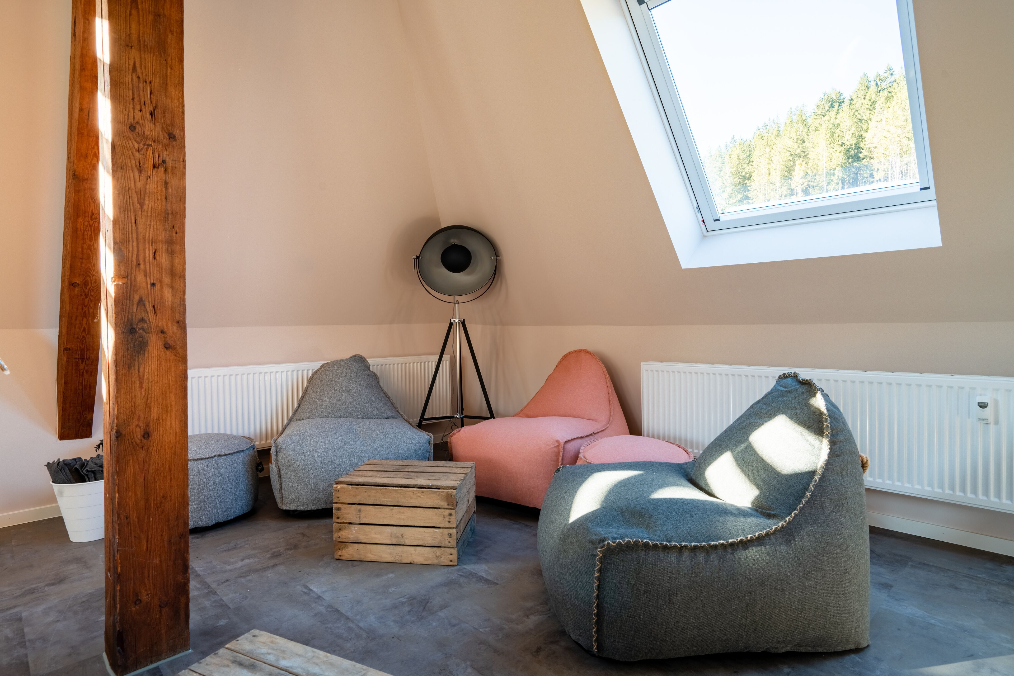 Una stanza accogliente con soffitto spiovente, un lucernario e un termosifone. Sul pavimento, due sacchi di fagioli e una cassa di legno.