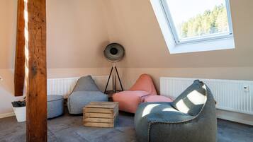Een gezellige kamer met schuine wanden, dakraam en radiator. Op de vloer staan twee loungestoelen en een houten kist.