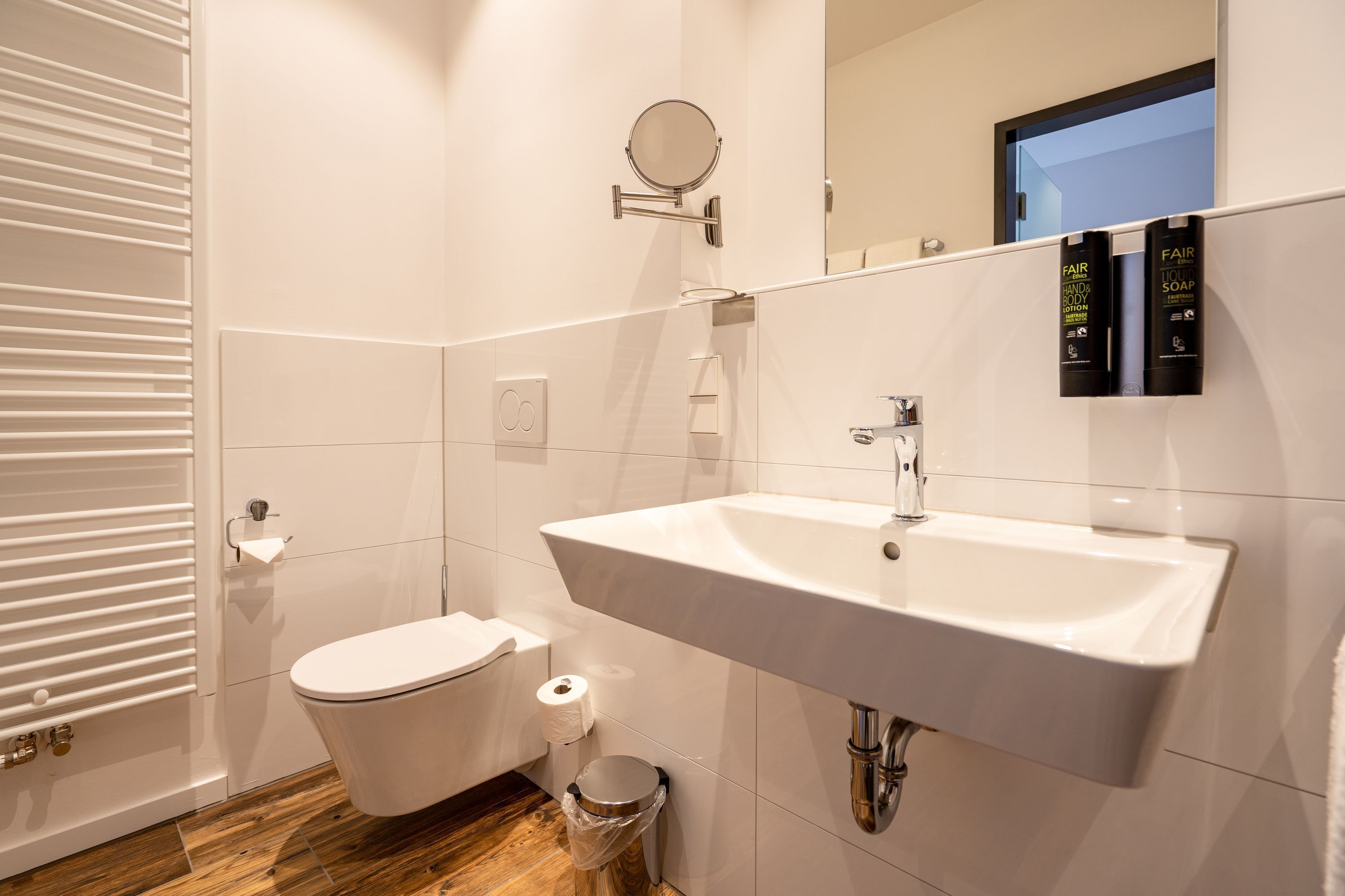 Een moderne badkamer met een wit wastafel, toilet en spiegel.