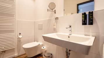Een moderne badkamer met een wit wastafel, toilet en spiegel.
