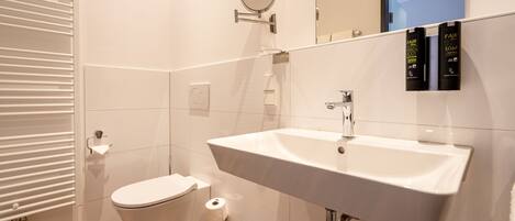 A modern bathroom with a white sink, toilet, and mirror.