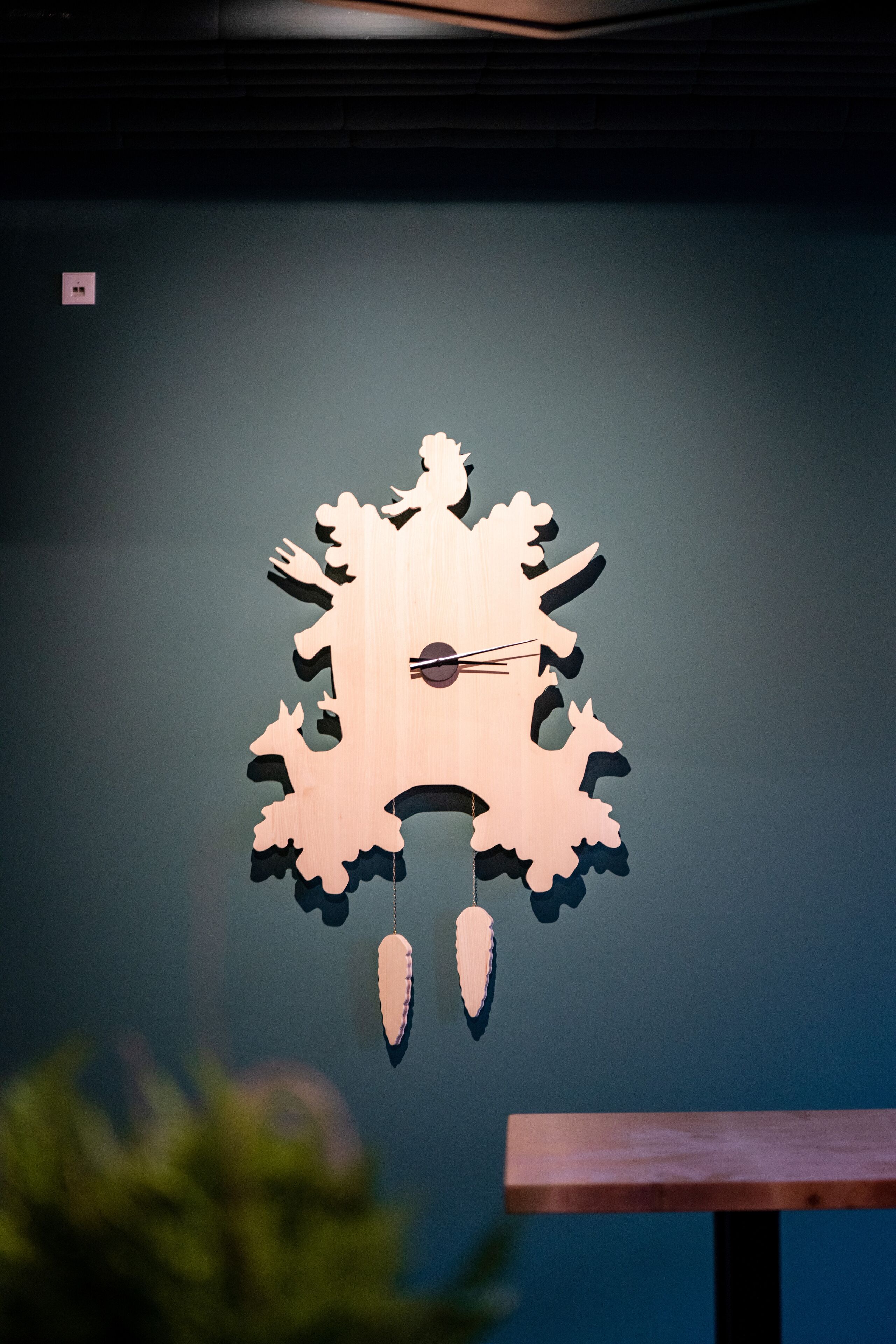 Eine an der Wand befestigte Holz-Wanduhr mit einem einzigartigen Design, inklusive Zifferblatt und Zeigern.