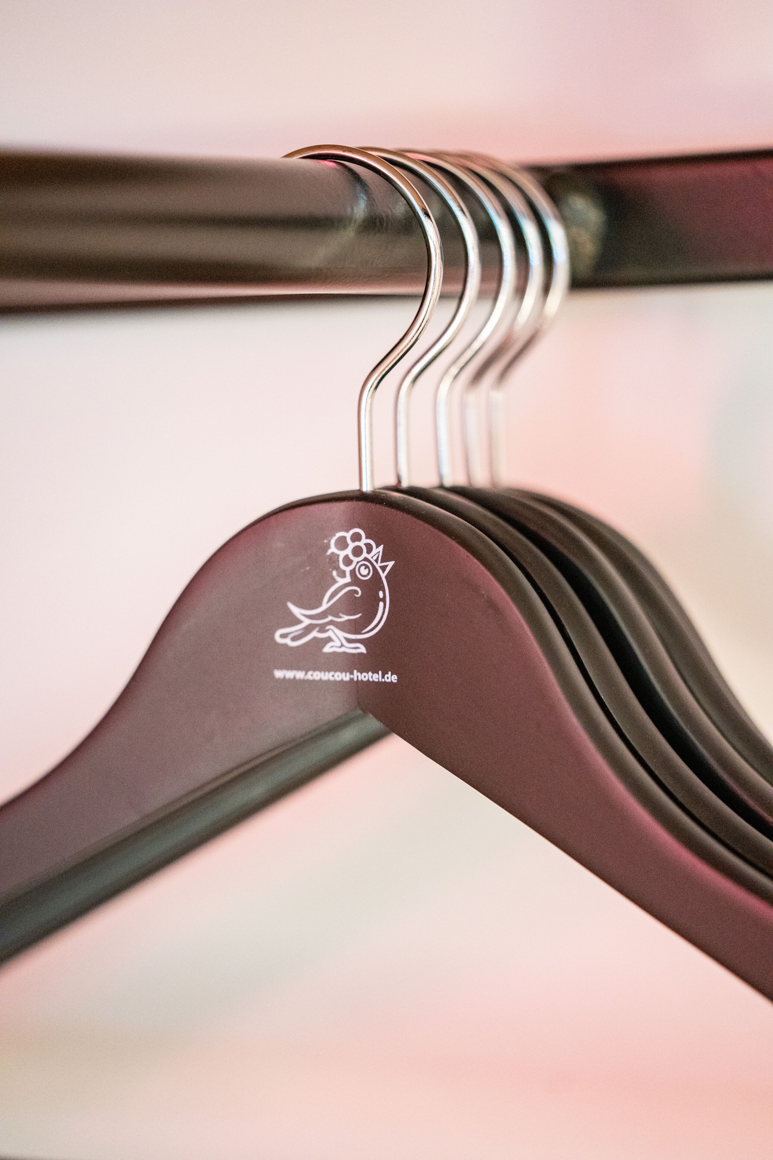 A close-up of a metal hanger with a logo and website address.