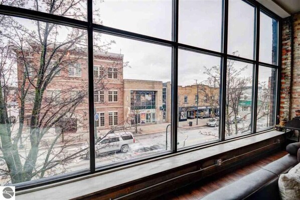 A room with large windows offering a view of the street and buildings outside. - Downtown Luxury Traverse City Loft Union/State St (Traverse City)