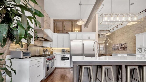 Una cocina moderna con armarios blancos, electrodomésticos de acero inoxidable y una isla grande con taburetes de bar.