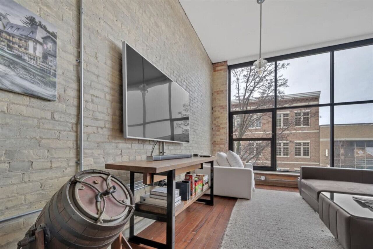 Un salon moderne avec une grande télévision, un tonneau en bois et un canapé blanc.