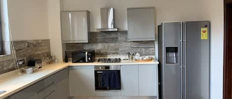 Casa adosada Signature | Cocina privada | Frigorífico grande, microondas, horno y placa de cocina