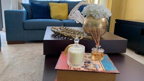A living room with a blue sofa, a coffee table with decorative items, and a bookshelf.