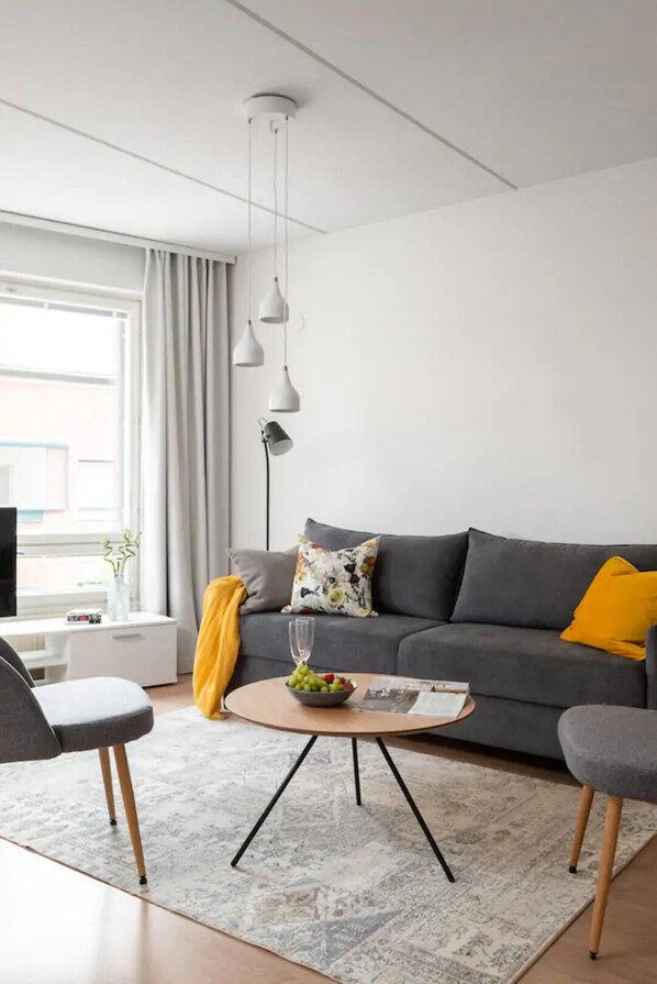 A modern living room with a grey sofa, a coffee table, and a TV on a stand.