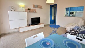Ett kompakt bostadsutrymme med ett litet kök, en matplats och en säng.