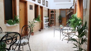 A courtyard with a tiled floor, potted plants, and metal chairs. - The Garden Bed and Breakfast (Las Palmas de Gran Canaria)
