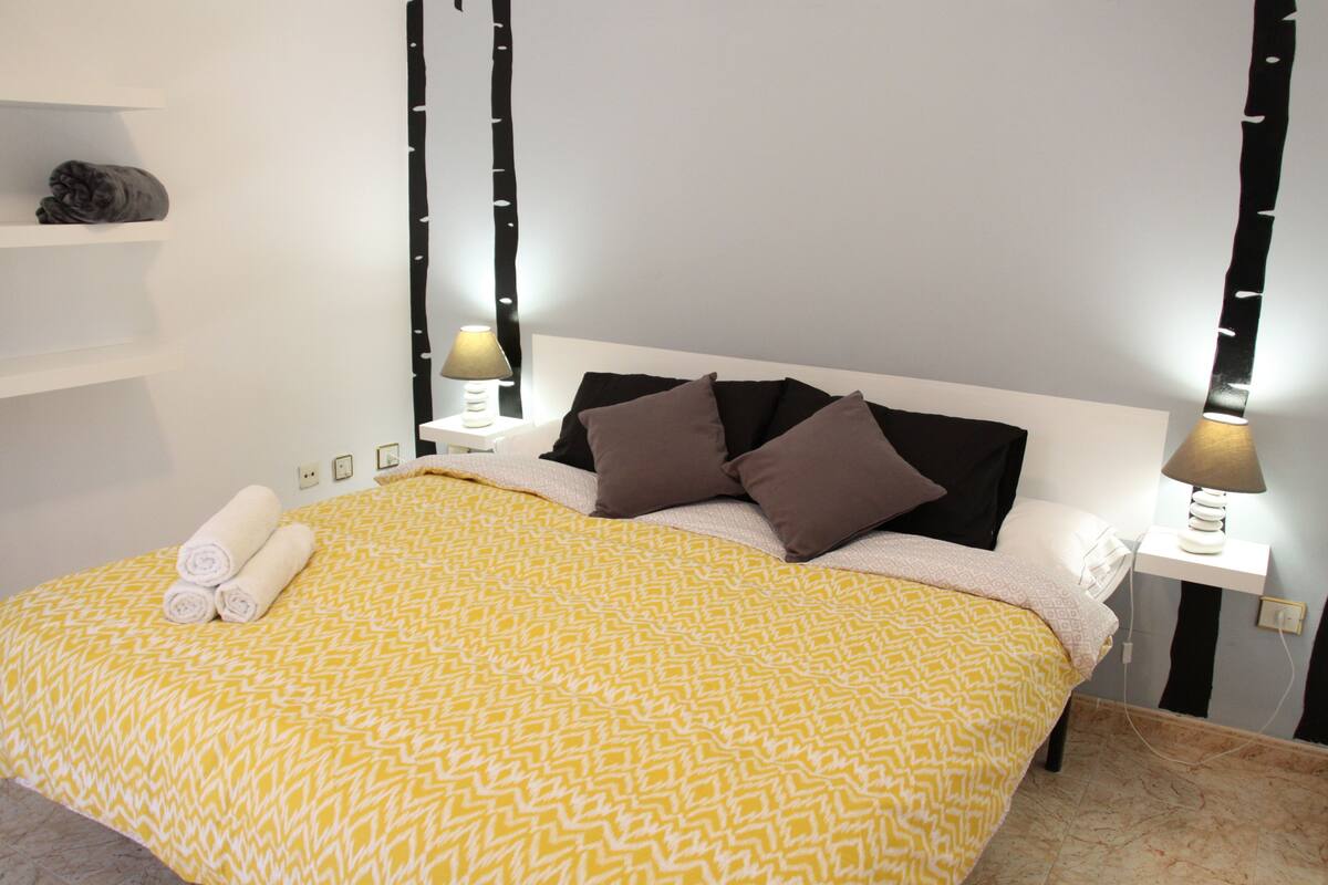 A neatly made bed with a patterned bedspread, two bedside lamps, and a headboard.