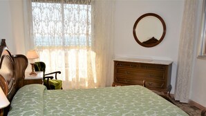 A bedroom with a bed, a dresser, a mirror, and a window with curtains. - Sant Telm A - Calafell (Calafell)