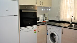A compact kitchen with a refrigerator, oven, microwave, coffee maker, and washing machine. - Sant Telm A - Calafell (Calafell)
