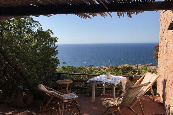 Une terrasse avec une table et des chaises donnant sur la mer.