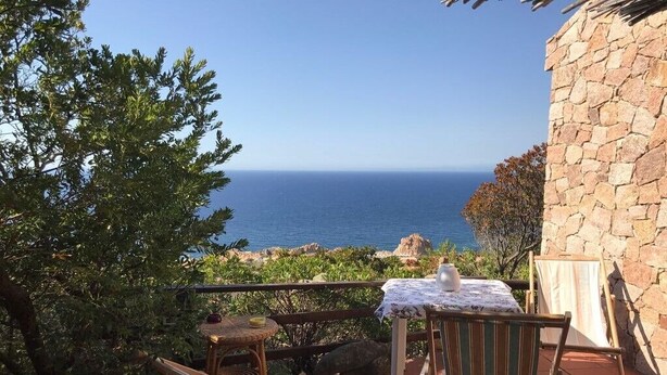 Une terrasse avec une table et des chaises, offrant une vue panoramique sur l’océan.