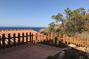 Une terrasse avec une clôture en bois, un sol carrelé et une vue sur la mer.