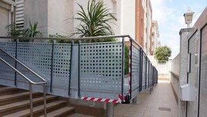 A staircase with metal railings and a red and white striped barrier at the bottom. - Apartment Barcino - Calafell (CALAFELL)