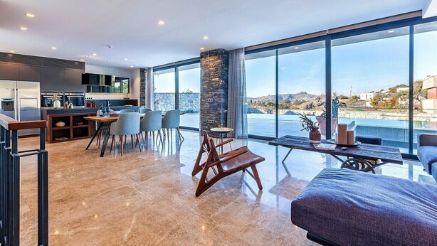 Una cocina moderna con comedor, ventanas amplias con vista al mar y una zona de estar acogedora con vistas.