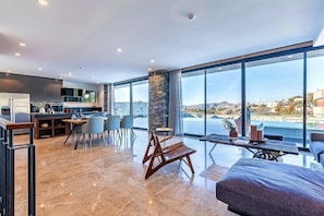 Une cuisine moderne avec un coin repas, de grandes fenêtres offrant une vue sur la mer et un espace salon confortable avec vue.