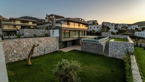 Una casa moderna con fachada de piedra, techo plano y césped cuidado.