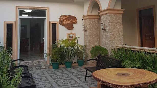 A courtyard with a wooden table and benches, potted plants, and a sign reading "Casa Feliciano". - Batanes Casa Feliciano (Basco)