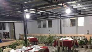 A dining area with tables set for a meal, surrounded by potted plants and a patterned floor. - Batanes Casa Feliciano (Basco)