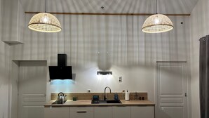A modern kitchen with two pendant lights, a built-in stove, and a sink. - La Maison de Paul & Margaux (Chateauneuf-de-Galaure)