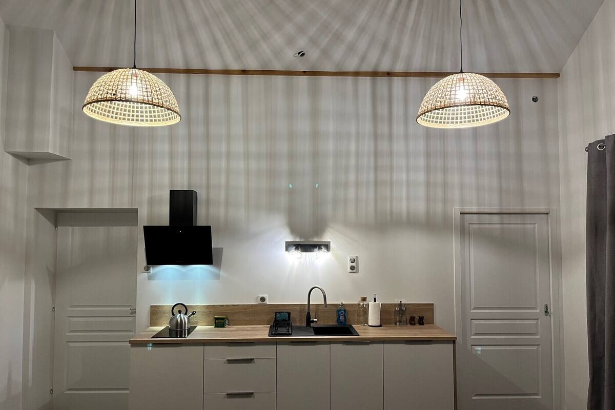 A modern kitchen with two pendant lights, a built-in stove, and a sink.