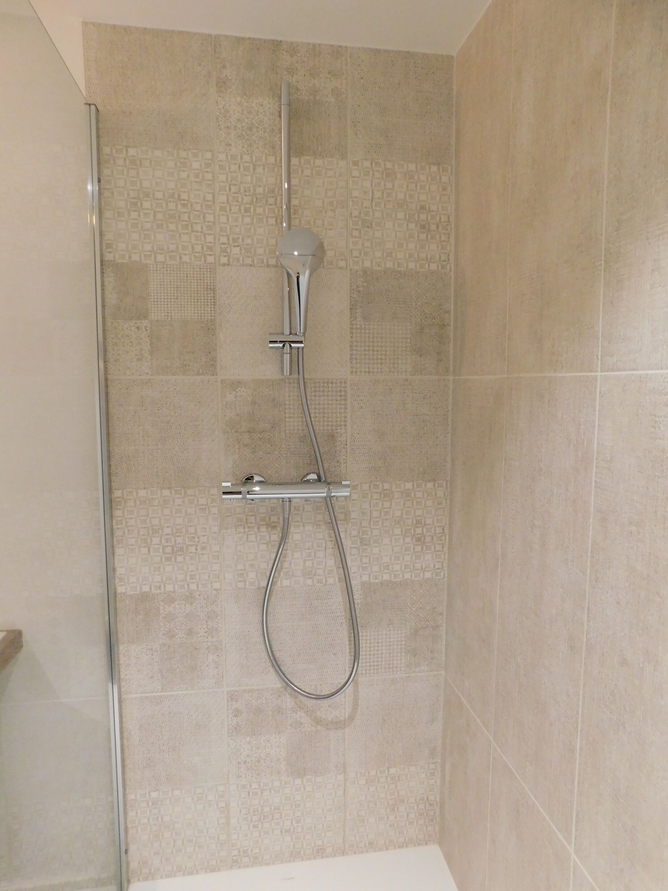 A shower with a glass door and a handheld showerhead.