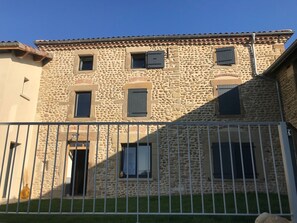 Un edifici de pedra amb diverses finestres i una tanca metàl·lica al primer pla.